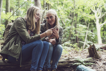 Twin sister in forest using tablet.