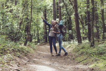 Twin sister hiking in forest pointing at tree.