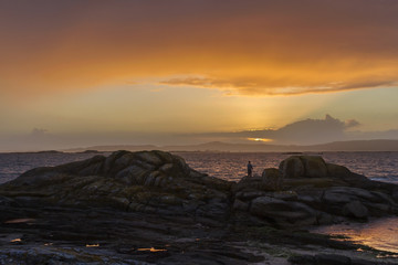 Obraz premium Angler on the rocks at dusk