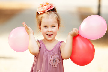 Portrait of laughing and playing birthday girl holding balloons