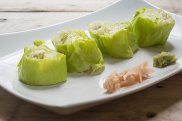 Salad roll vegetables with salad dressing in dish on wooden for