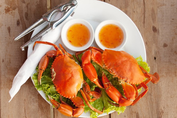 Two crabs on a platter and two saucers with hot sauce