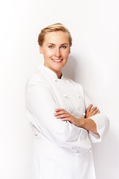 Young woman chef smiling over white background in chef's outfit.