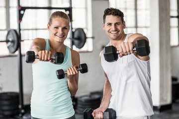 couple exercising with dumbbells in gym