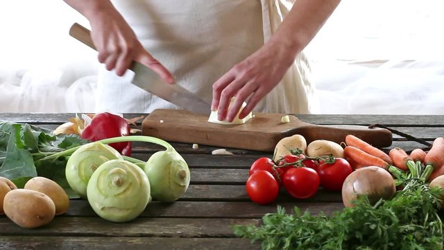 Woman slice vegetables. Woman slice onion on wooden table. Rustic style.