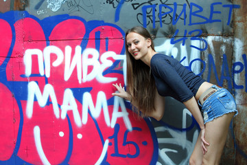 Young woman in front of a Russian graffiti saying hello Mama