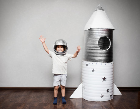 Happy child dressed in an astronaut costume playing with hand ma