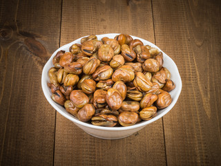 Broad beans in white bowl on wooden table