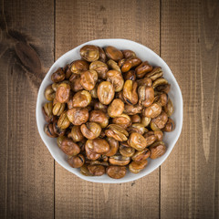 Broad beans in a white bowl on wooden boards top view