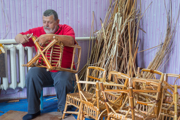 Senior master of wicker-work making a stool