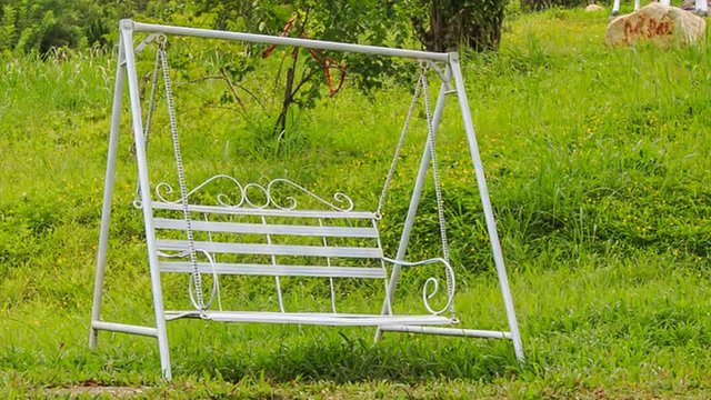 metal swing bench against green grass in tourist park