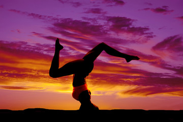 silhouette of woman legs apart doing head stand