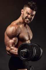 Fototapeta na wymiar Muscular bodybuilder guy doing exercises with dumbbells