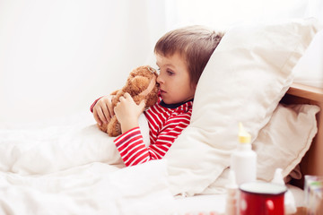 Sick child boy lying in bed with a fever, resting