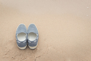 Fototapeta premium canvas shoes on sand beach