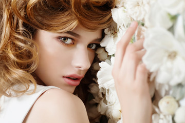 Beautiful young girl on a background of white flowers, the concept of beauty and health