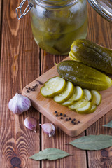 Pickles in bank with garlic and pepper on a table