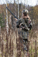 Woman hunter in camouflage in autumn forest
