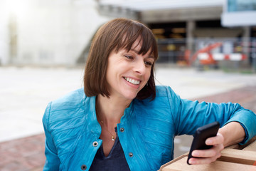 Mature woman smiling and looking at mobile phone