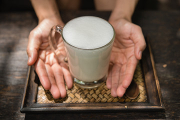 Woman holding a glass of hot milk relax in the cafe.