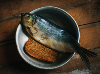 Salted fish and dark bread on metal plate.
