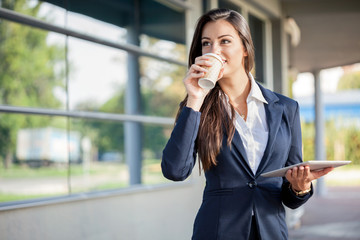 Businesswoman outside with coffee and tablet