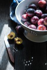 Fresh plums in rustic colander