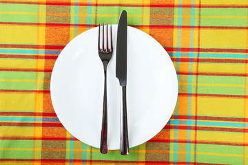 Empty white plate on colorful napkin