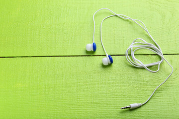 White headphones on a green wooden table
