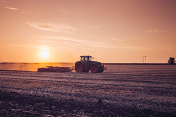 Tractor on the field by sunset.