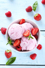Ice cream in bowl with strawberries and raspberries on blue wood