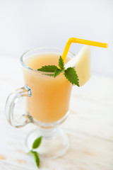 Glass of melon cocktail on white wooden background