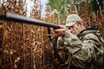 man hunter with shotgun in forest