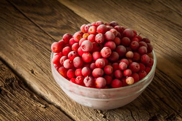frozen cranberry in bowl on wooden background