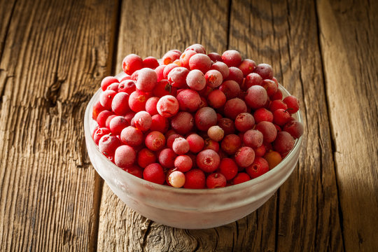 frozen cranberry in bowl on wooden background