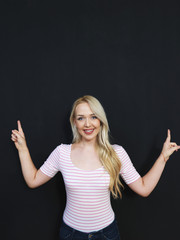 Caucasian woman standing in front of a dark chalkboard. The chal