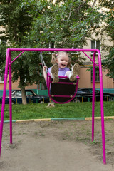 little girl with pigtails on a swing at playground