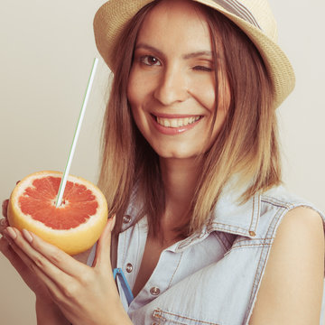 Happy woman in hat drinking grapefruit juice. Diet