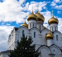 Fototapeta na wymiar white Cathedral with its golden domes and crosses against blue sky and clouds in Yaroslavl, Russia