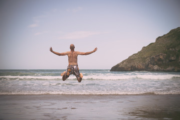 Young man jumping in the beach shore