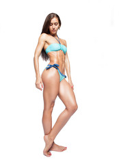 fit caucasian woman in blue bikini staying on white background