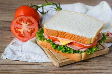 sandwich with ham, cheese and vegetables on wood table