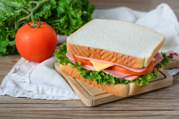 sandwich with ham, cheese and vegetables on wood table