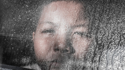 Young Asian boy trapped behind a window looking out