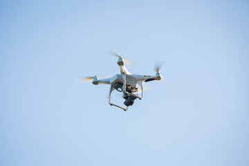 Drone hovering on the blue sky.