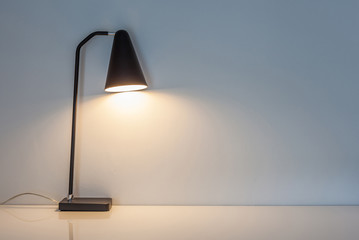 The modern desk lamp illuminate on the wall background.