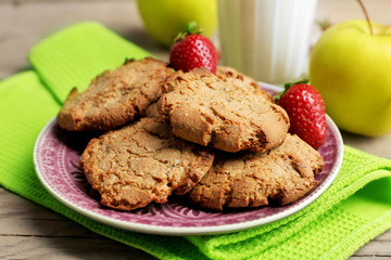Homemade cookies with fruits and glass of milk on table close up