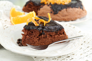 Portion of Cake with Chocolate Glaze and orange on plate, on wooden background