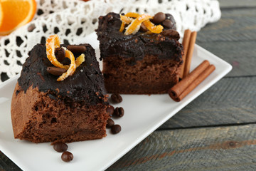 Portion of Cake with Chocolate Glaze and orange on plate, on wooden background