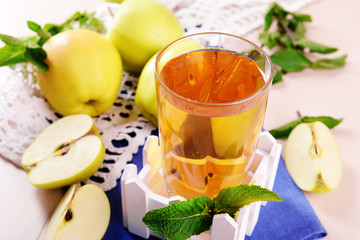 Glass of apple juice with fruits and fresh mint on table close up